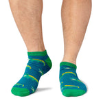 Green socks with a repeated crocodile pattern worn by a person on a white background