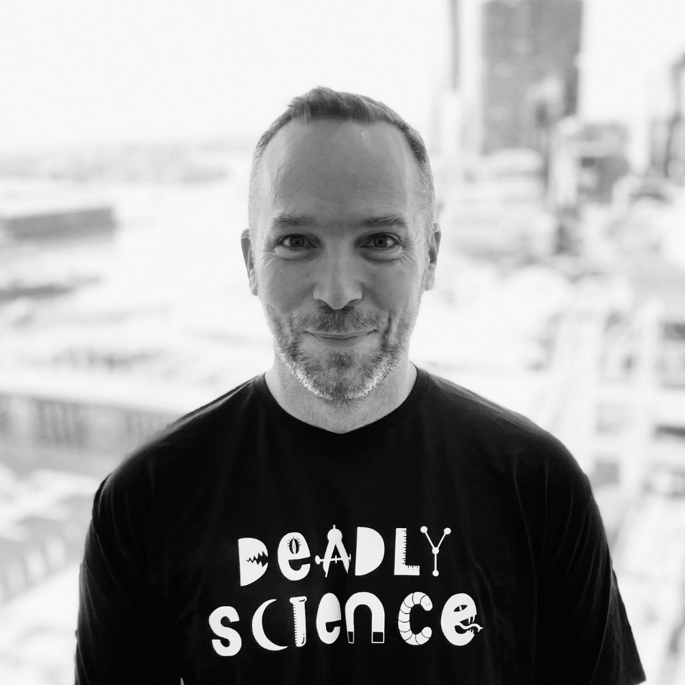 Black and white portrait of Board member Kurt Lackovic, wearing a DeadlyScience t-shirt. 