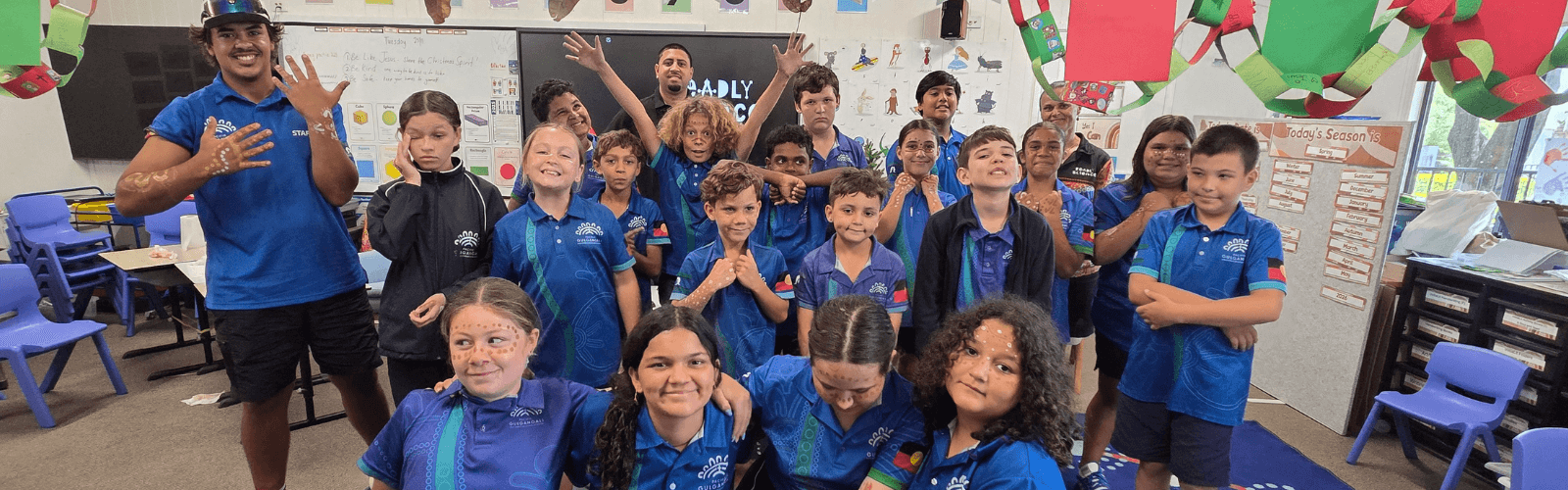 Group of leaners in blue uniforms with educators in a classroom setting